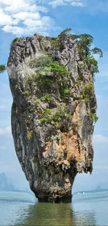 Vertical island rock formation in Phang Nga Bay with a blue sky backdrop.