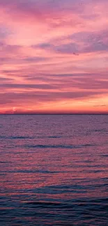 Pink ocean sunset over calm water with vibrant sky.