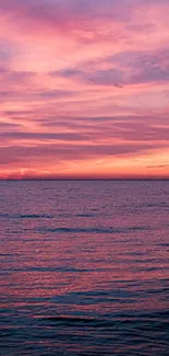 Vivid pink sunset over calm ocean waves, natural beauty wallpaper.