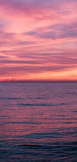 Pink sunset over a calm ocean with vibrant clouds.