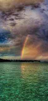 Vibrant rainbow over serene ocean waters with cloudy sky backdrop.