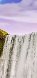 Scenic waterfall with a rainbow under a serene sky.