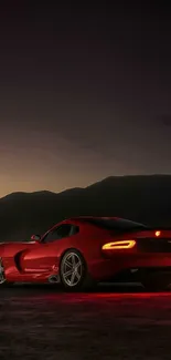 Red sports car at night with mountains.