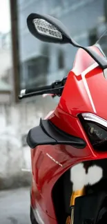 Vibrant red motorcycle with sleek design against urban backdrop.