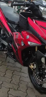 Red motorcycle with sleek sporty design on pavement.