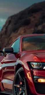 Sleek red sports car with mountain backdrop.