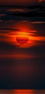 Stunning red sunset over water with clouded sky.