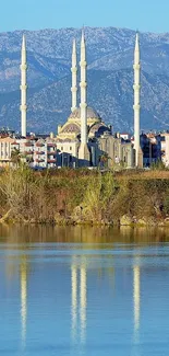 Scenic cityscape with river reflection and mountain background.