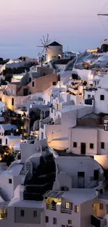 Iconic Santorini view at dusk with white buildings and a peach sky.