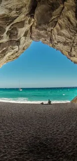 Scenic view of a beach through a cave opening with ocean and sky.