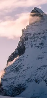 Snow-covered mountain peak amidst misty clouds.