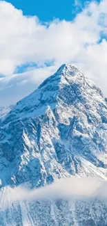 Snowy mountain peak under blue sky with clouds.