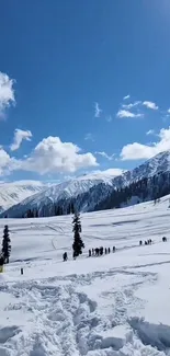 Snowy mountain landscape with a bright blue sky and scattered clouds.