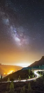 Starry night sky over winding road in scenic mountain landscape.