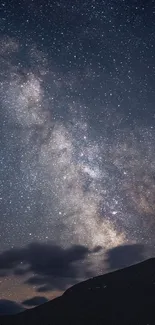 Starry night sky with Milky Way above silhouetted mountains.