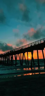 Silhouette of a pier at sunset over ocean waves.