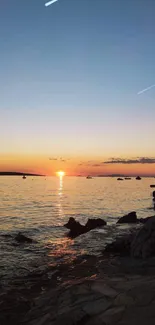 Vibrant sunset over a rocky beach, with a serene ocean view.