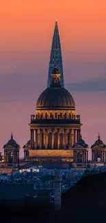 Illuminated historic building at sunset with vibrant orange and purple sky.