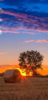 Serene field with hay bale and sunset sky in vibrant hues.