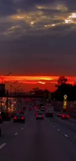 Highway at sunset with vibrant orange sky and city lights.