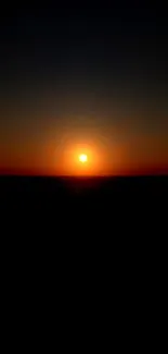 Sunset wallpaper with glowing sun and dark horizon for mobile phones.