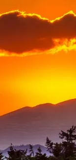 Vibrant orange sunset over mountain silhouette.