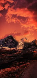 Fiery sunset over snow-capped mountains with vibrant orange hues and dramatic clouds.