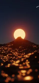 Orange sunset behind mountain with glowing ocean waves.