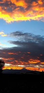 Breathtaking sunset with mountain silhouette under vivid orange and blue sky.