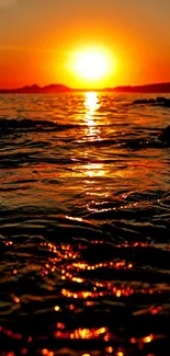 Beautiful sunset over calm ocean water with vibrant orange hues.