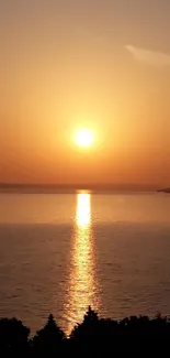 Sunset over ocean with orange sky and serene waters.