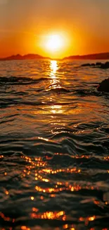 Orange sunset over ocean with sun reflecting on water.