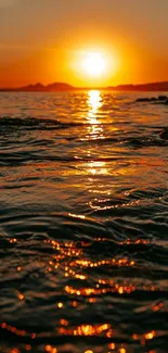 Sunset over ocean with vivid orange hues reflecting on water.