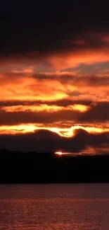 Dramatic sunset over a calm lake with orange and red hues.