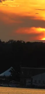 Beautiful sunset over lake with orange sky and dark silhouette of trees.