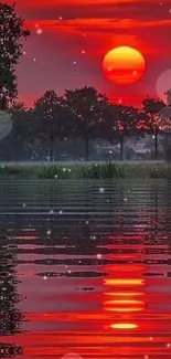 Vibrant red sunset reflecting on calm water with trees.