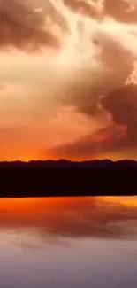 Beautiful sunset reflecting over calm water with silhouetted mountains.