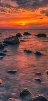 Vibrant sunset over rocky ocean shore wallpaper.