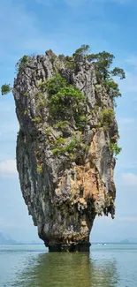 Tall limestone island in calm blue waters.