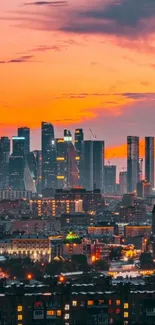 Skyline at sunset with illuminated buildings in a vibrant orange sky.