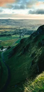 Scenic valley with lush green hills and a winding road under dramatic clouds.