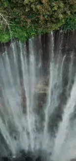 Aerial view of a vertical waterfall with lush green surroundings.