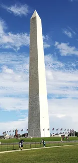 Washington Monument under a blue sky with surrounding flags.