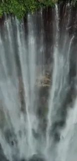 Aerial view of a majestic waterfall cascading down lush greenery.