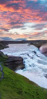 Beautiful waterfall under a vibrant sunset sky with lush surroundings.