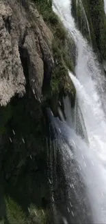 Waterfall cascading down a rocky cliff with lush greenery.