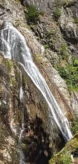 Cascading waterfall in lush, rocky landscape wallpaper.