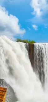 Majestic waterfall under a blue sky with clouds.