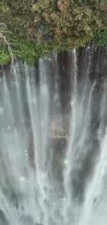 Aerial view of majestic waterfall with mist and lush greenery.