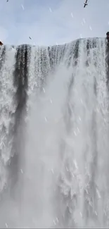 Majestic waterfall cascading with serene skies in the background.